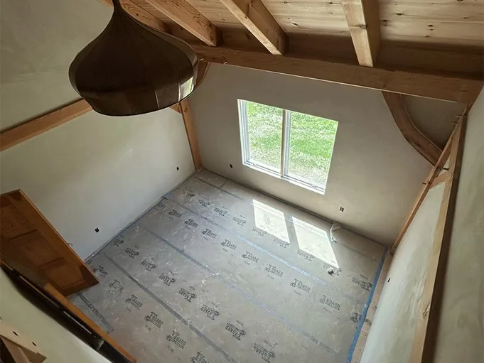 American Clay walls in a timber frame bedroom with an exposed truss and a copper pendant