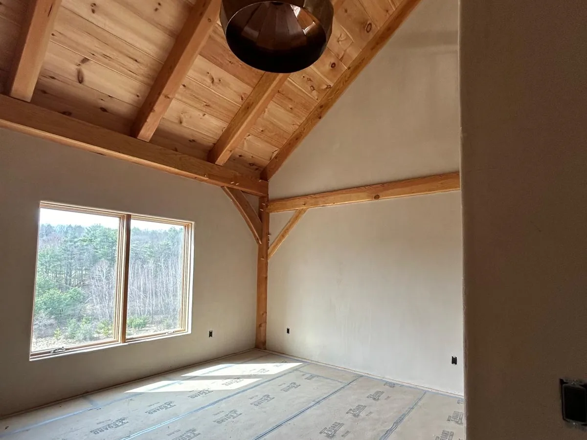 American Clay bedroom walls under a cathedral pine ceiling with a corner window