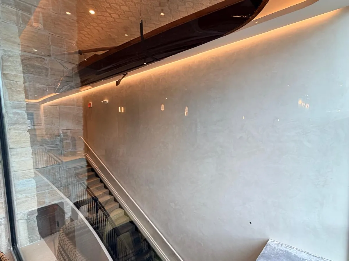 Commercial lobby with polished plaster walls, a curved staircase and a suspended canoe