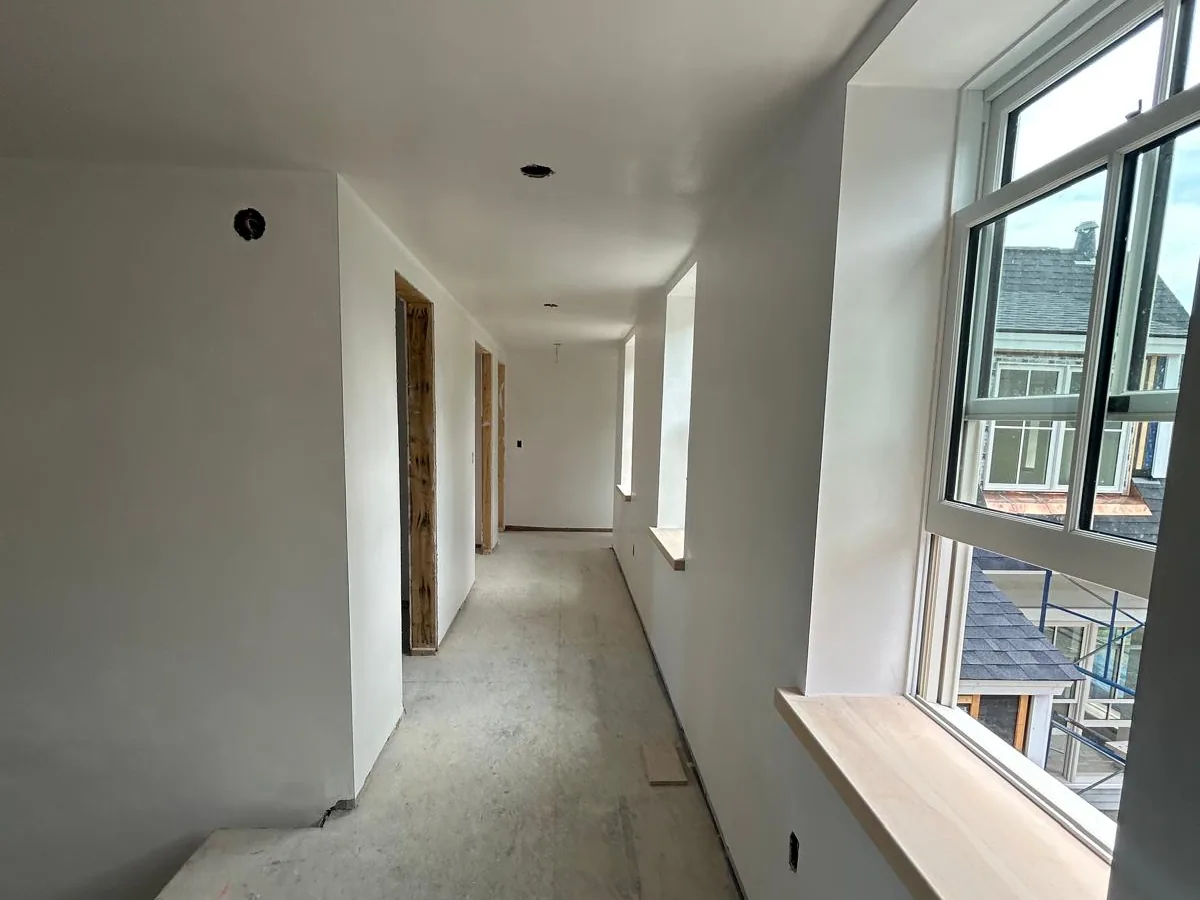 Long bright corridor with walls skim finished smooth beside a run of windows
