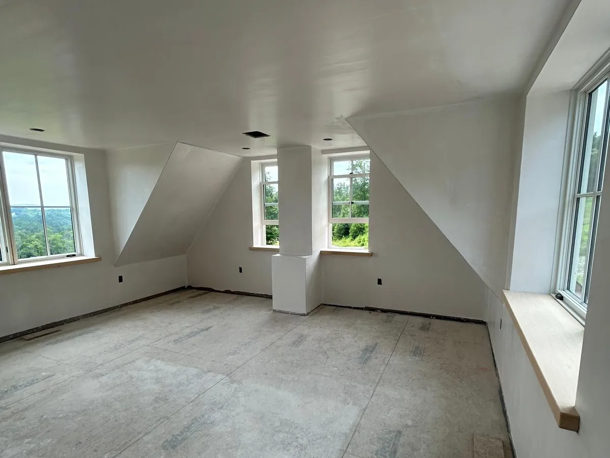 Finished drywall in an upper room with twin dormer windows