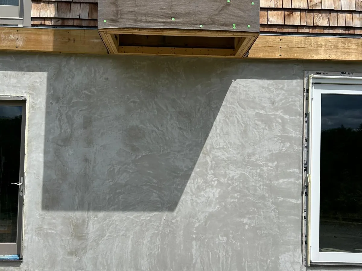 Detail of stucco base coat meeting shingle siding on an exterior wall