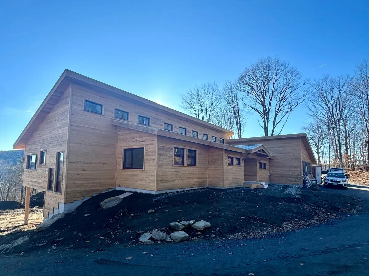 Modern timber clad building finished, seen from the drive under a clear sky