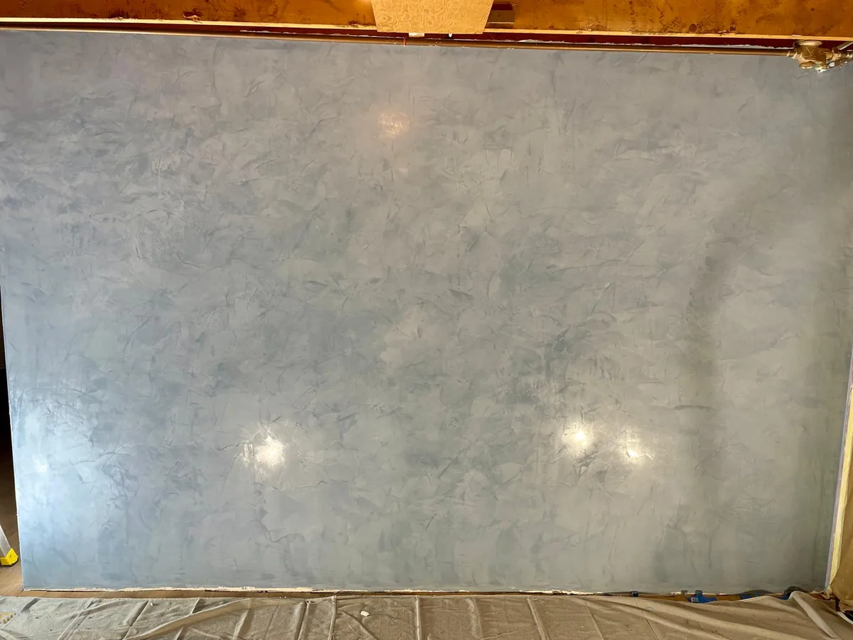 Wide microcement feature wall finished smooth, lit from below