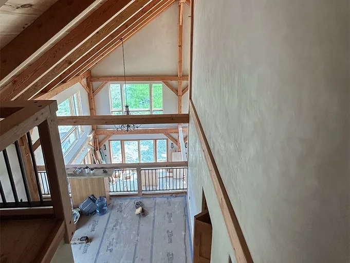 Timber frame great room with lime plastered walls seen from the mezzanine