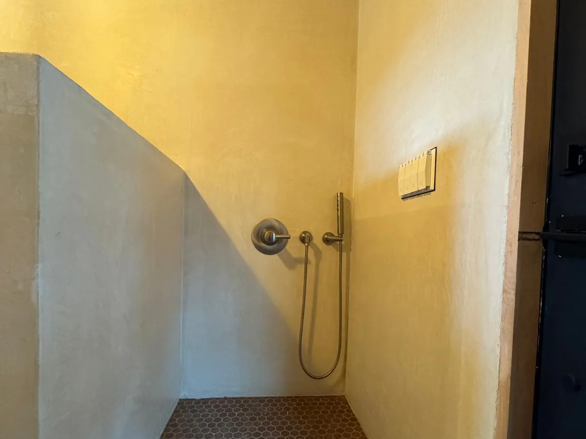 Walk in shower finished in warm toned tadelakt with no grout lines and a tiled shower pan
