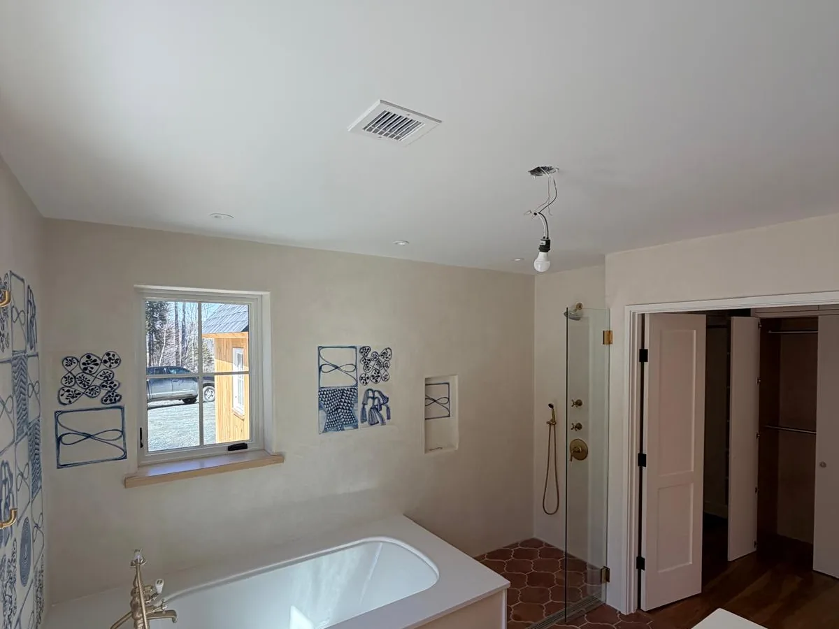 Plastered bath surround around a built in tub, with a terracotta hexagon floor in the shower